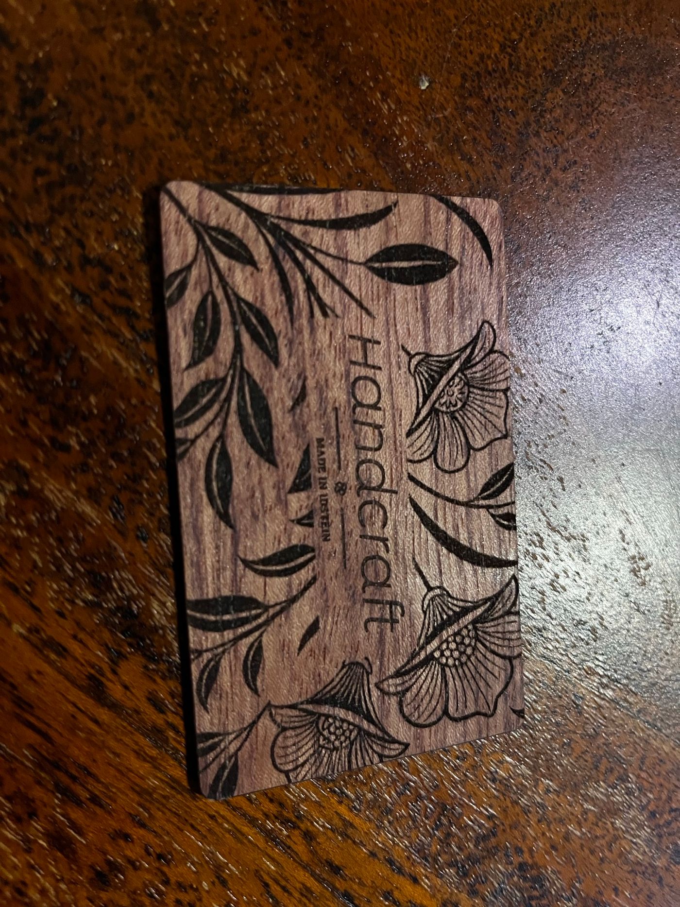 Eine NFC-Visitenkarte aus dunklem Holz mit einer feinen, per Laser gravierten floralen Ornamentik im Jugendstil.